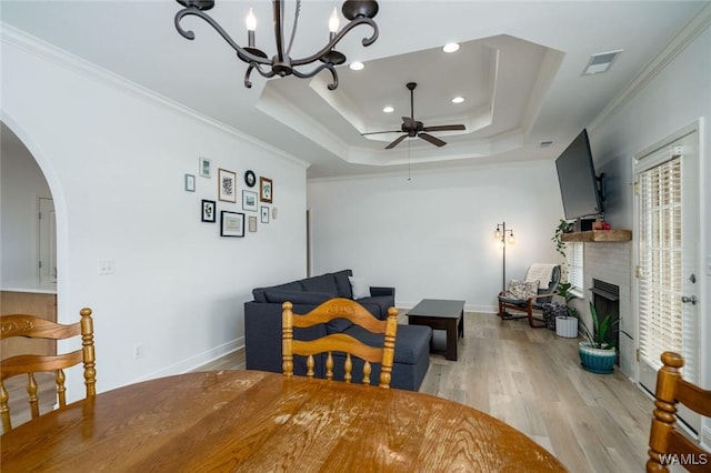 dining room with a tray ceiling, ornamental molding, and light wood-type flooring