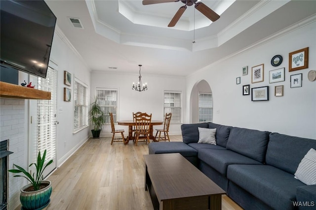 living room featuring a fireplace, ornamental molding, light hardwood / wood-style floors, and a raised ceiling