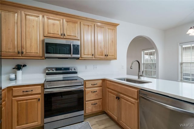 kitchen featuring appliances with stainless steel finishes, light hardwood / wood-style floors, sink, and kitchen peninsula