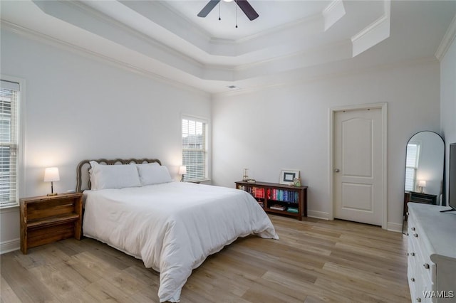 bedroom featuring crown molding, light hardwood / wood-style floors, and a raised ceiling