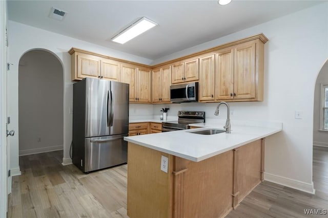 kitchen featuring sink, appliances with stainless steel finishes, light hardwood / wood-style floors, light brown cabinetry, and kitchen peninsula