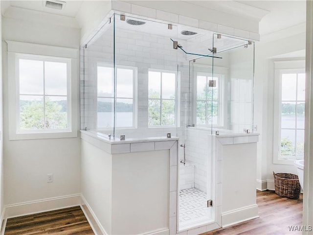 bathroom featuring a wealth of natural light, wood-type flooring, walk in shower, and ornamental molding