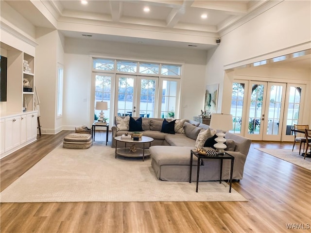 living room featuring built in features, beam ceiling, french doors, and light hardwood / wood-style flooring