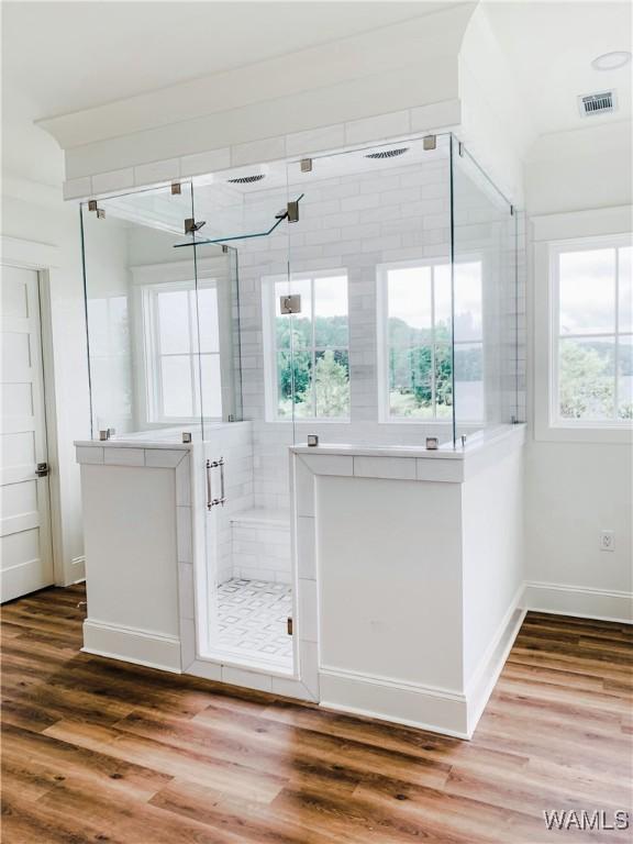 bathroom with a shower with door, plenty of natural light, and hardwood / wood-style flooring