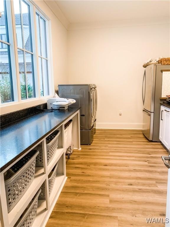 clothes washing area featuring cabinets, crown molding, independent washer and dryer, and light wood-type flooring