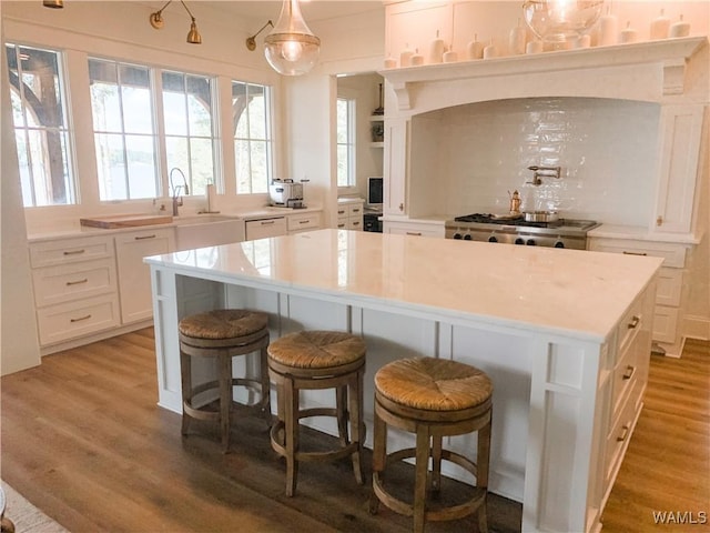 kitchen featuring white cabinets, decorative light fixtures, a center island, and wood-type flooring