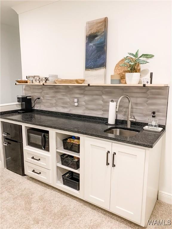 bar with sink, backsplash, white cabinetry, and dark stone counters