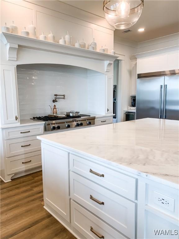 kitchen with stainless steel appliances, white cabinetry, and light stone counters