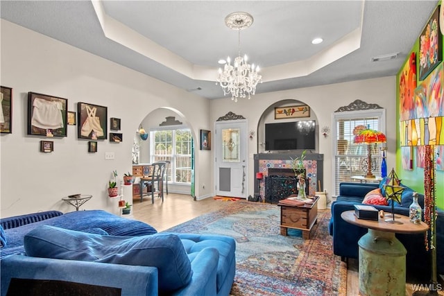 4468 21st St, Northport, AL 35476 - living area featuring a raised ceiling, arched walkways, wood finished floors, a chandelier, and a fireplace