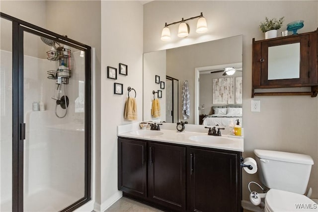 bathroom with tile patterned floors, toilet, vanity, a shower with door, and ceiling fan