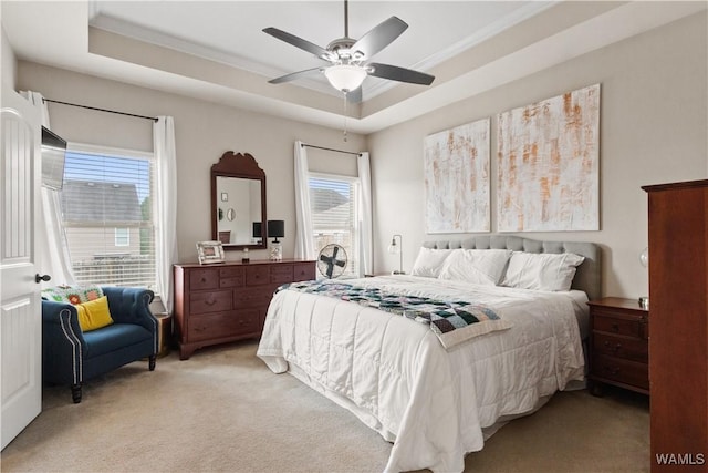 bedroom featuring ornamental molding, light colored carpet, ceiling fan, and a tray ceiling