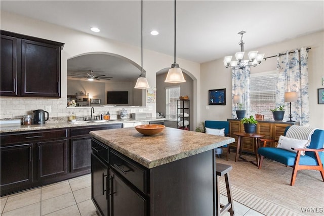 kitchen with sink, hanging light fixtures, light tile patterned floors, a kitchen island, and decorative backsplash