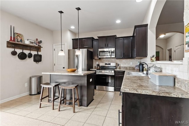 kitchen with pendant lighting, sink, stainless steel appliances, tasteful backsplash, and light tile patterned flooring