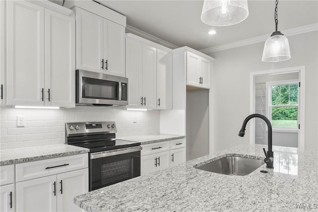 kitchen featuring crown molding, decorative backsplash, stainless steel appliances, and a sink