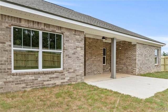 rear view of house featuring a patio area, roof with shingles, ceiling fan, and brick siding