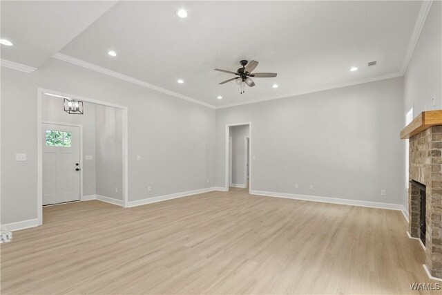 unfurnished living room with light wood-type flooring, a brick fireplace, crown molding, and baseboards