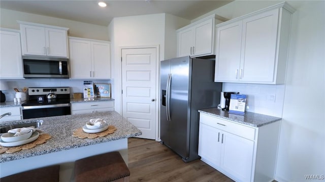 9349 Havenridge Loop, Tuscaloosa, AL 35405 - kitchen with stainless steel appliances, white cabinetry, wood finished floors, decorative backsplash, and light stone counters
