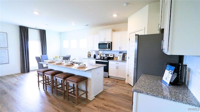 9349 Havenridge Loop, Tuscaloosa, AL 35405 - kitchen featuring stainless steel appliances, a breakfast bar, light wood-type flooring, white cabinetry, and recessed lighting