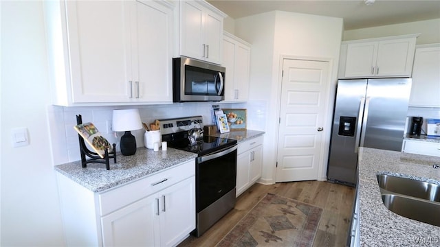 9349 Havenridge Loop, Tuscaloosa, AL 35405 - kitchen featuring appliances with stainless steel finishes, light wood-style flooring, backsplash, white cabinetry, and a sink