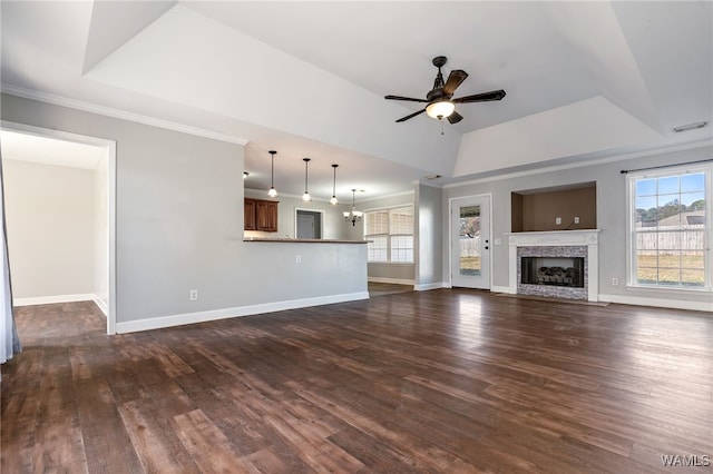 unfurnished living room featuring a tray ceiling, dark wood-type flooring, ceiling fan with notable chandelier, and ornamental molding