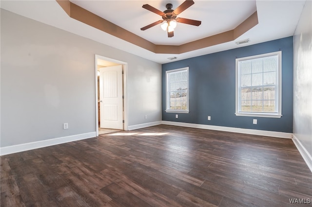 spare room featuring dark hardwood / wood-style floors, ceiling fan, and a tray ceiling