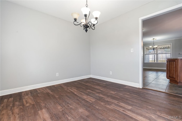 spare room with dark hardwood / wood-style flooring, crown molding, and a chandelier