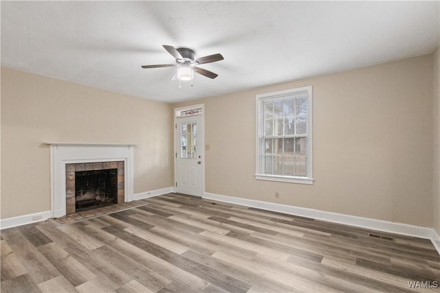 unfurnished living room featuring ceiling fan, a fireplace, and light wood-type flooring