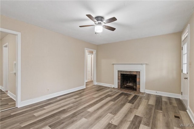 unfurnished living room featuring ceiling fan, wood-type flooring, and a tile fireplace