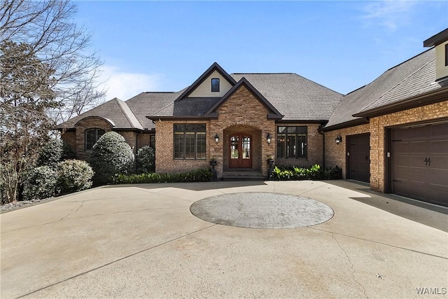 10416 Harbourtowne Dr, Northport, AL 35475 - french country style house with curved driveway, brick siding, an attached garage, and a shingled roof
