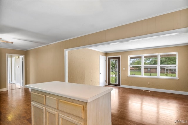 kitchen with crown molding, light brown cabinets, a kitchen island, and dark wood-type flooring