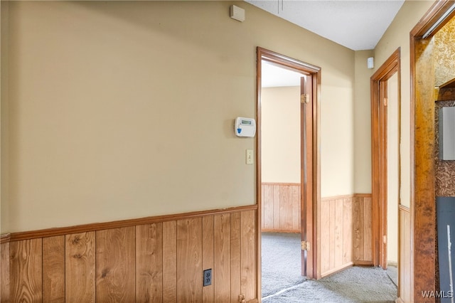 hallway with light carpet and wood walls