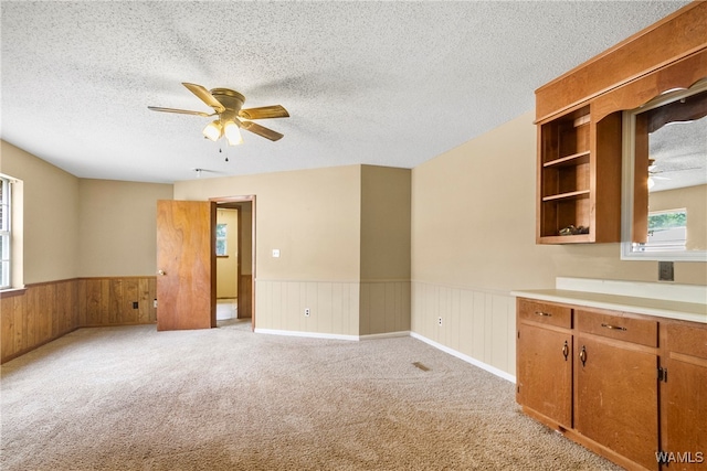 interior space featuring a textured ceiling, ceiling fan, and wooden walls