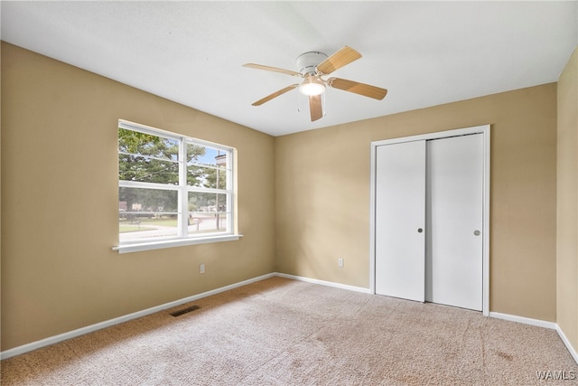 unfurnished bedroom with a closet, light colored carpet, and ceiling fan