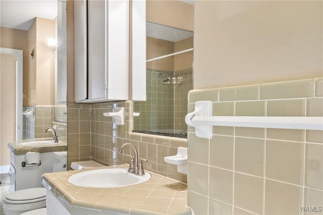 bathroom with tiled shower, sink, tile walls, and toilet