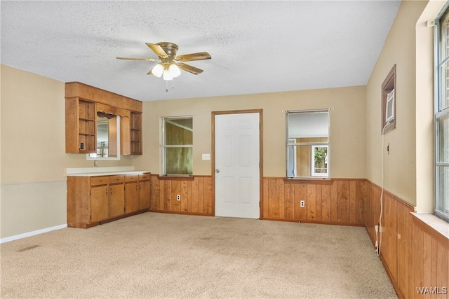 interior space with light carpet, a textured ceiling, ceiling fan, and wood walls