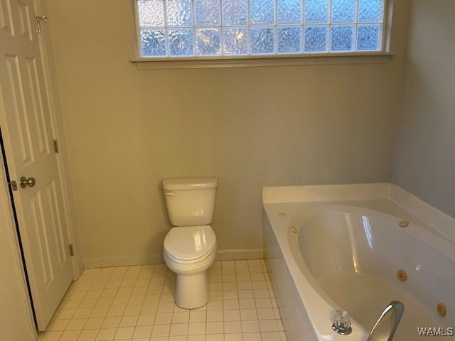 bathroom featuring tile patterned flooring, a washtub, and toilet