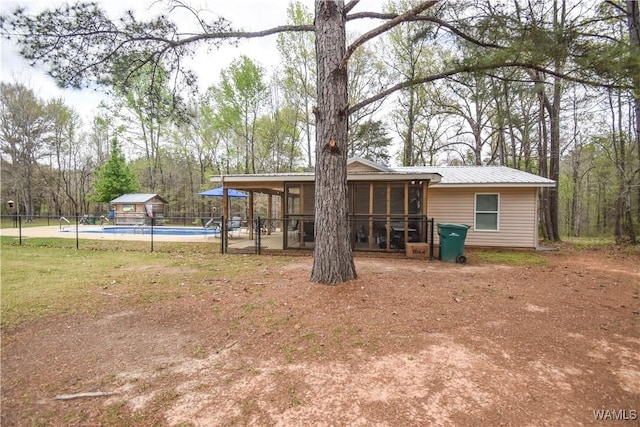 15337 Strawberry Ln, Northport, AL 35475 - rear view of property featuring a fenced in pool, an outdoor structure, fence, metal roof, and a sunroom