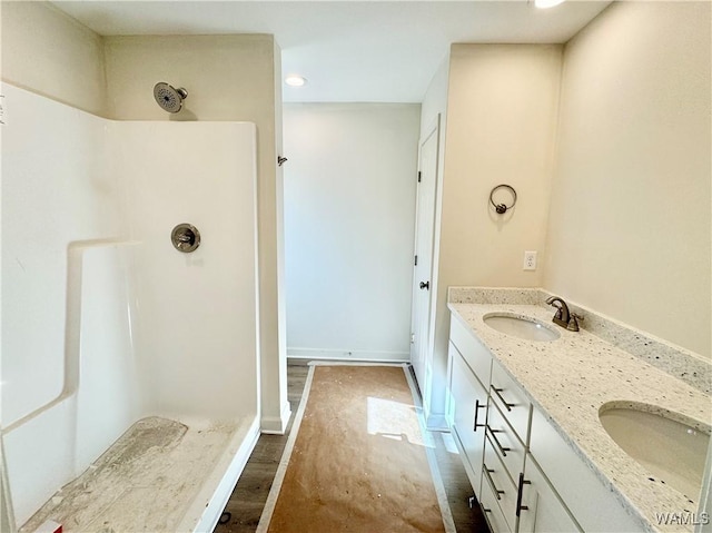 bathroom featuring hardwood / wood-style flooring, vanity, and a shower