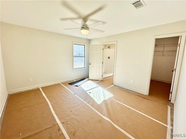 unfurnished bedroom featuring a walk in closet, a closet, and ceiling fan