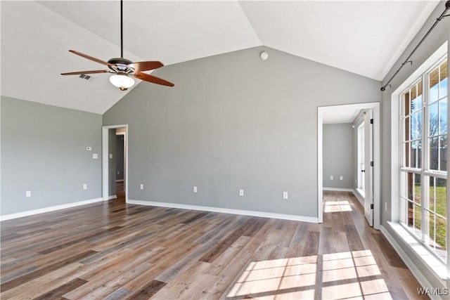 spare room featuring a ceiling fan, visible vents, wood finished floors, baseboards, and high vaulted ceiling