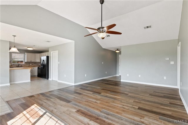 unfurnished living room with visible vents, light wood-style flooring, baseboards, and a ceiling fan