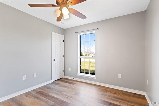 empty room featuring a ceiling fan, baseboards, and wood finished floors