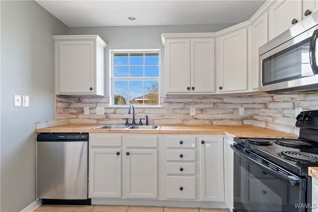 kitchen featuring tasteful backsplash, wooden counters, white cabinets, stainless steel appliances, and a sink