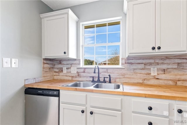 kitchen with butcher block countertops, a sink, stainless steel dishwasher, white cabinetry, and decorative backsplash