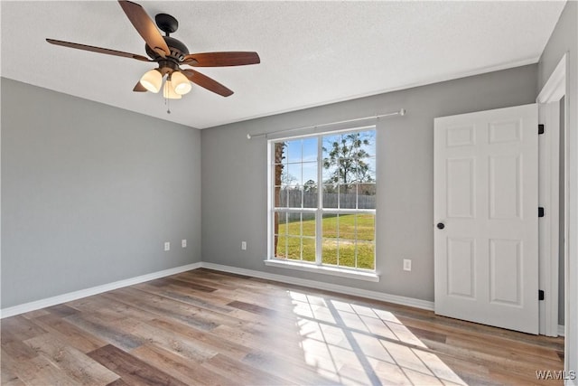 spare room featuring ceiling fan, baseboards, a textured ceiling, and wood finished floors