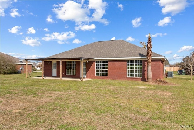 back of house with brick siding, a patio, a shingled roof, and a yard