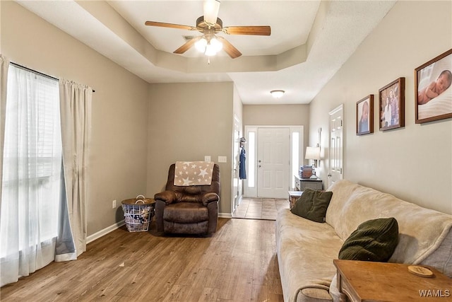 4458 19th St, Northport, AL 35476 - living room with hardwood / wood-style flooring, a tray ceiling, ceiling fan, and baseboards