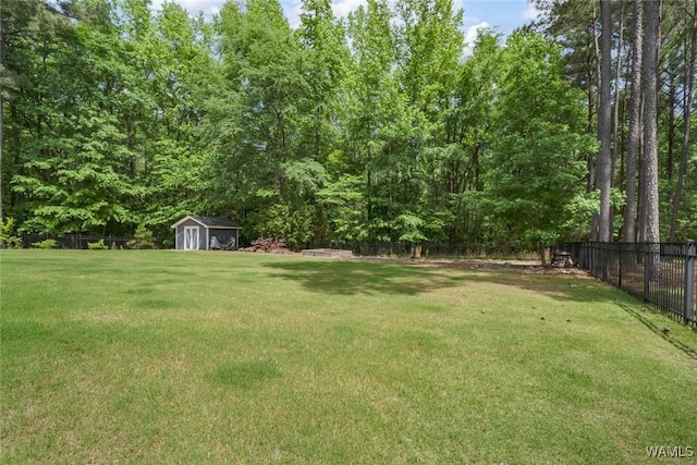 view of yard with a fenced backyard, a view of trees, an outbuilding, and a shed
