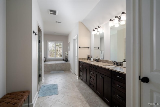 bathroom with tile patterned floors, vanity, and tiled bath