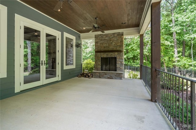 view of patio with an outdoor stone fireplace, ceiling fan, fence, and french doors